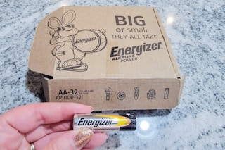 a box on a counter and a hand holding a battery