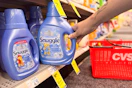 person grabbing a bottle of snuggle fabric softener off the shelf