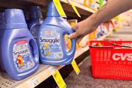 person grabbing a bottle of snuggle fabric softener off the shelf