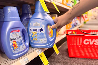person grabbing a bottle of snuggle fabric softener off the shelf