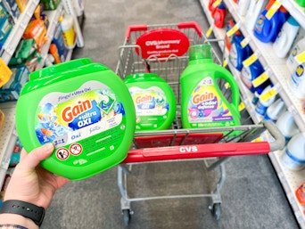 person holding gain flings over a cart with more gain detergent 