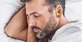 a person wearing earplugs while laying in bed