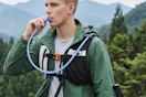 man drinking out of his running vest