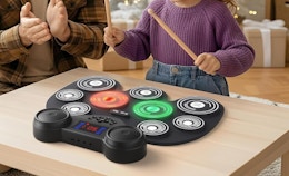 a kid playing on electronic drums on a wooden table