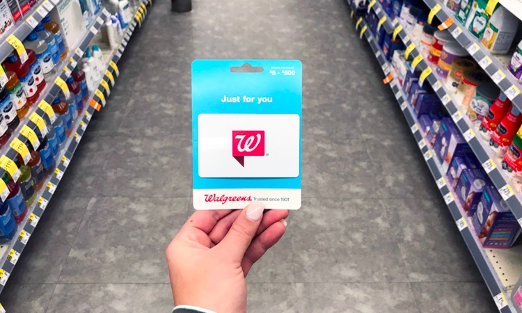 Someone holding a Walgreens gift card in the middle of an aisle in store