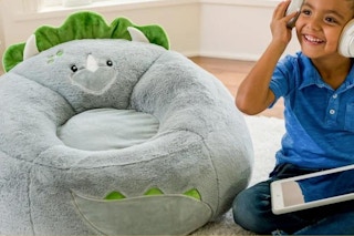 child sitting next to a dinosaur bean bag chair