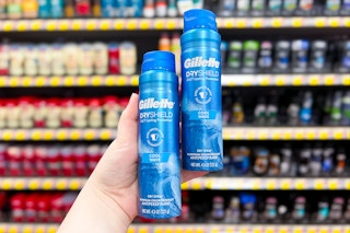 a hand holding two containers of Gillette dry spray