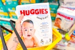 hand holding huggies diapers in a yellow shopping basket