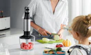 a person chopping food next to an immersion blender on a counter