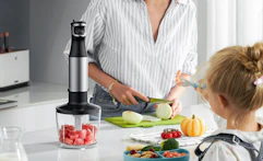 a person chopping food next to an immersion blender on a counter