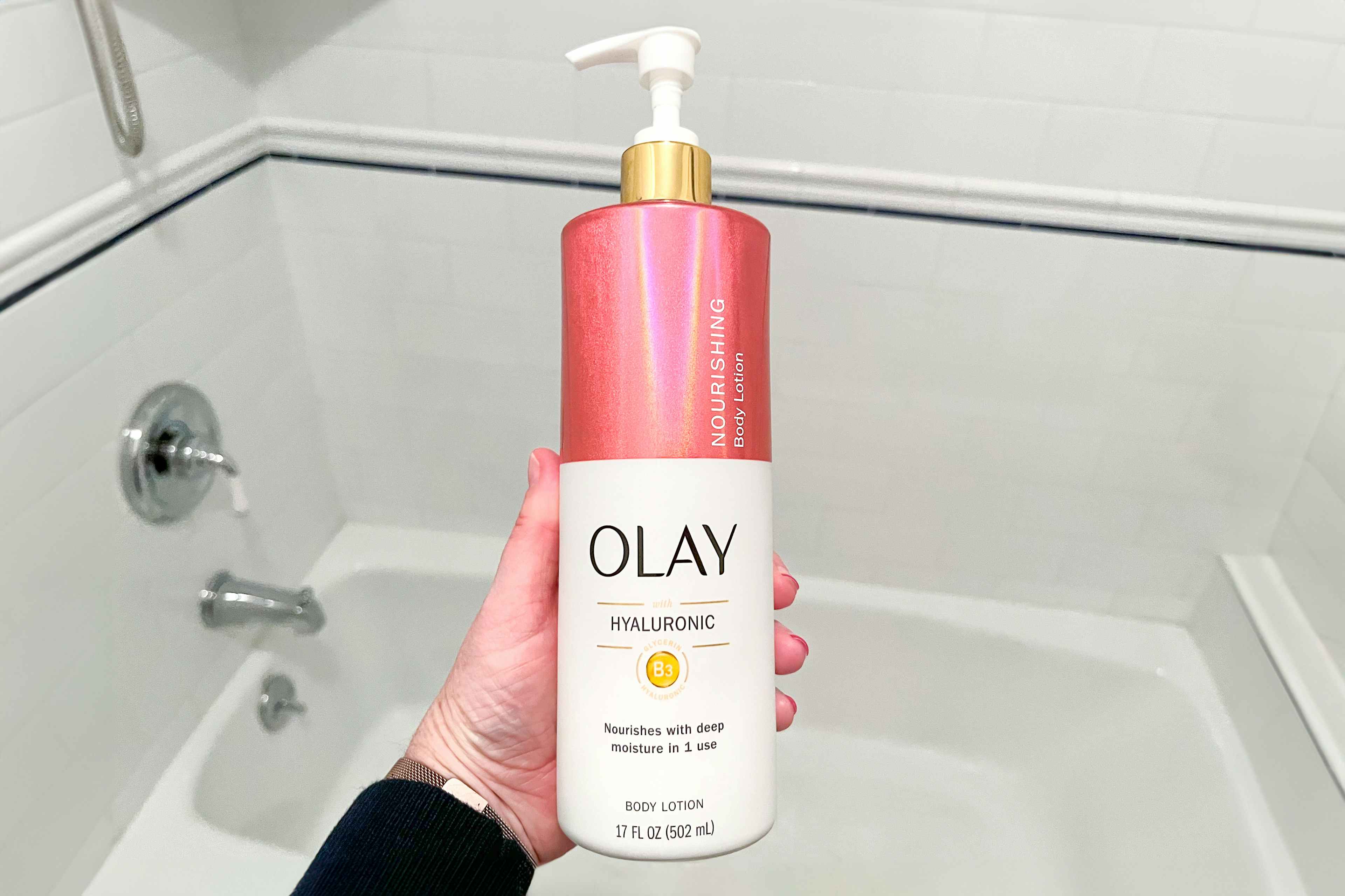 someone holding a bottle of olay lotion in a bathroom