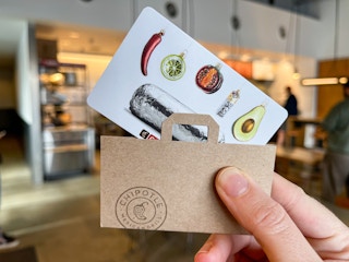someone holding chipotle gift card inside a Chipotle.