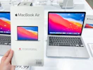 macbook air on display at costco with a hand holding a macbook air card