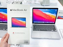 macbook air on display at costco with a hand holding a macbook air card