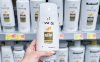 womans left hand holding white bottle of pantene pro v daily moisture conditioner