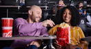 a couple at a movie theater with popcorn and a drink