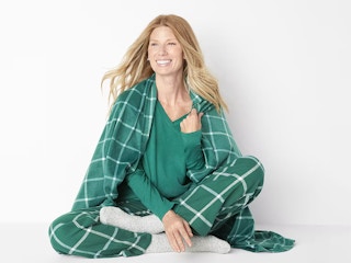 a woman wearing a 4-piece pj set that includes a shirt, pants, socks, and a shawl