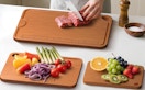 a person cutting up food on bamboo cutting boards