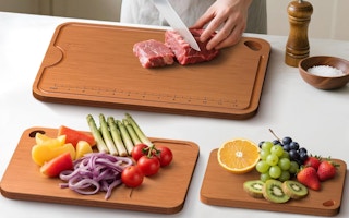 a person cutting up food on bamboo cutting boards