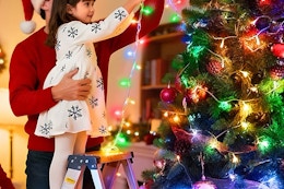 a girl putting up led lights on a tree with her family 