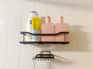 a pink shampoo and conditioner bottle in a shower caddy with beauty products