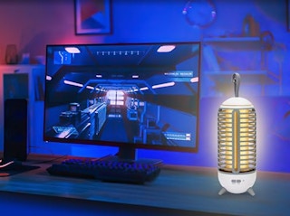 a bug zapper on a desk next to a computer monitor in a room with a blue light