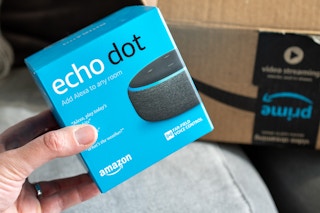 An Amazon Echo Dot in front of an open delivery box.