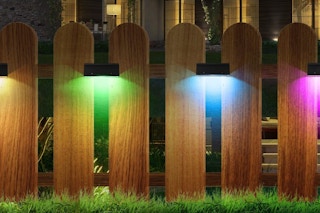 Deck lights in different colors lit on a fence