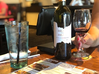 a bottle and glass of wine being held on a table near a glass of water