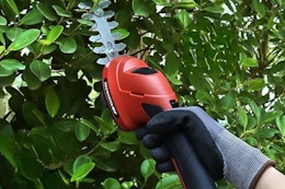 Hand holding cordless hedge trimmer. B0DRW81417