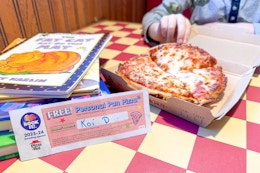 A pizza hut book it coupon next to a free personal pan pizza and a stack of books in a pizza hut restaurant