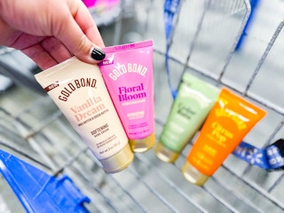 hand holding two bottles of gold bond scented hand cream with two in walmart cart