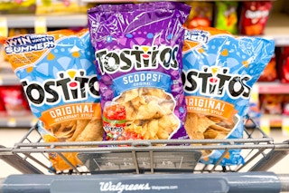 shopping cart filled with three bags of tortilla chips with product shelves in background