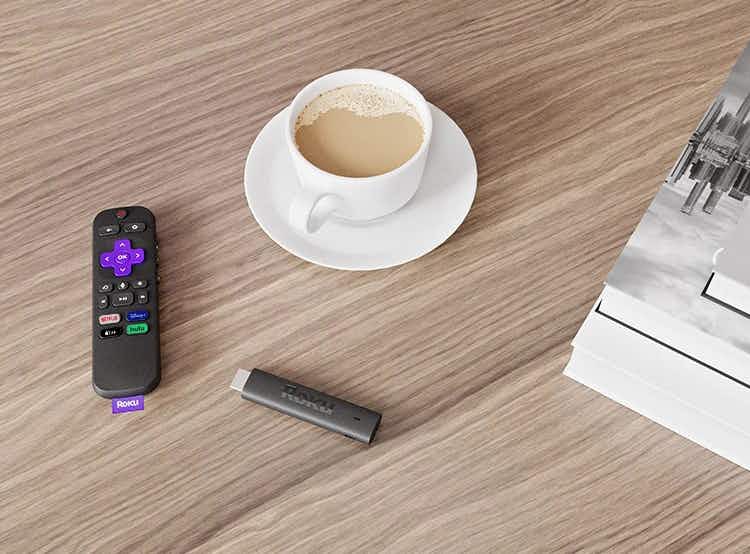 Roku remote and stick on desk with cup of coffee