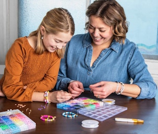 A mom and daughter making bracelets on a table