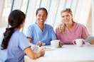 Group of nurses chatting, one nurse is. holding a tablet
