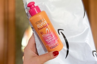 hand holding a bottle of l'oreal elvive no haircut conditioner cream next to an amazon envelope