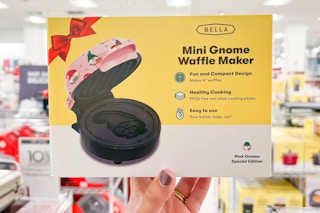 someone holding a mini waffle maker with christmas design