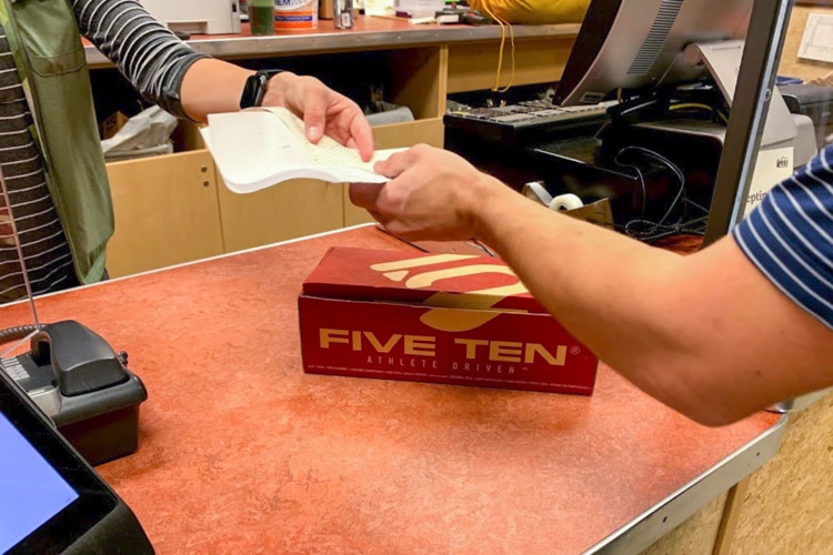 Man and employee exchanging a receipt at the returns counter in REI