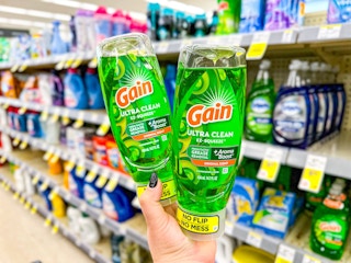 hand holding two bottles of gain ez squeeze dish soap in a store aisle
