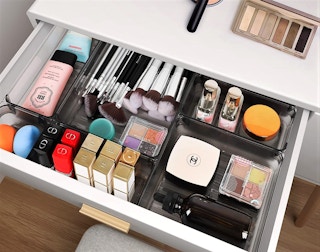 A clear desk drawer organizer filled with makeup items.