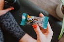 woman holding Kind Mini bar while sitting on a yoga mat