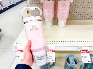 hand holding a stanley tumbler in front of a target shelf