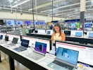 a person looking at laptops in walmart smiling
