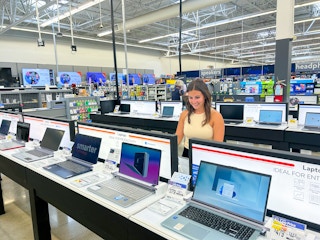 a person looking at laptops in walmart smiling