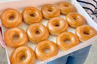 someone holding a dozen original glazed donuts from Krispy Kreme