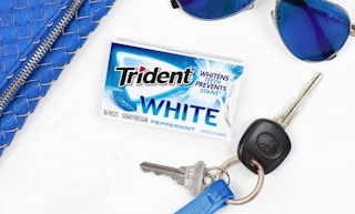 trident white gum on a white background with blue accessories around it