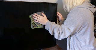 Someone using a microfiber cloth to clean the screen of their TV