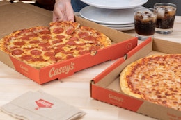 Someone taking a slice of pizza from a Casey's box