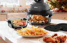 a portable air fryer on a counter with a plate of food